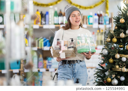 Young woman choosing gift basket in supermarket during X-mas Young woman choosing gift basket in supermarket during X-mas 125584991