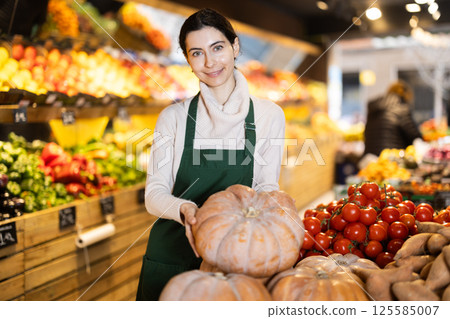 Woman seller checking pumpkin 125585007