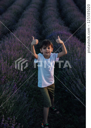 The boy shows fingers up in a field of lavender 125585020