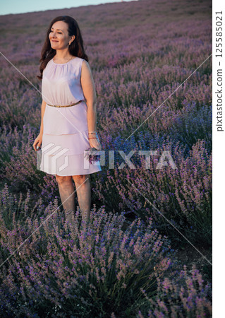 Woman in dress in lavender field before harvest Woman in dress in lavender field before harvest 125585021