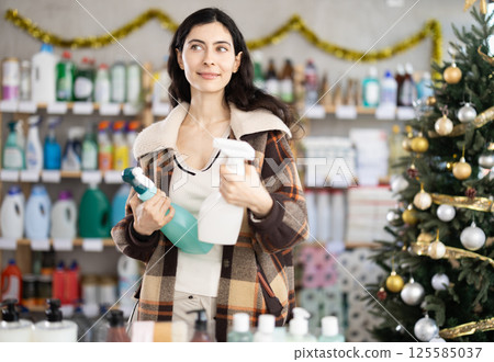 Young woman choosing cleaning spray in store during Christmas Young woman choosing cleaning spray in store during Christmas 125585037