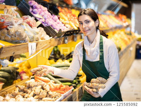 Female employee informs about arrival of ripe ginger, advertises product Female employee informs about arrival of ripe ginger, advertises product 125585092