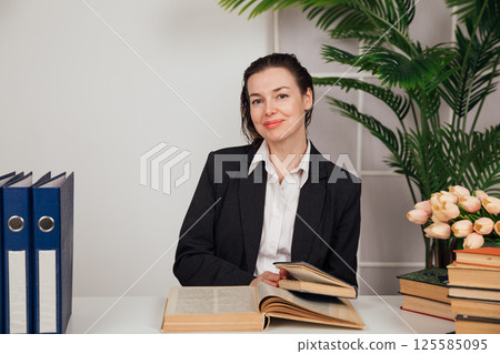 woman sitting at desk with books in office 125585095