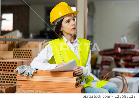Female supervisor taking notes while inspecting construction site indoors Female supervisor taking notes while inspecting construction site indoors 125585122