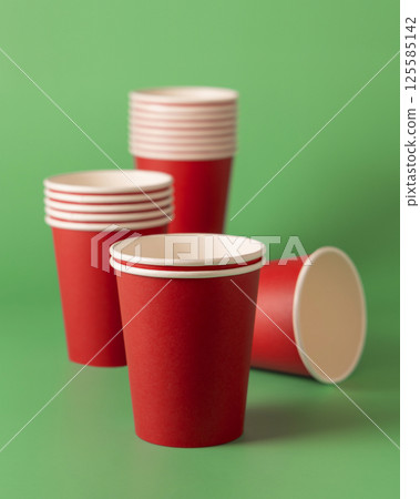 Disposable red paper cups on a green closeup, mockup. No plastic and sustainable Christmas Disposable red paper cups on a green closeup, mockup. No plastic and sustainable Christmas 125585142