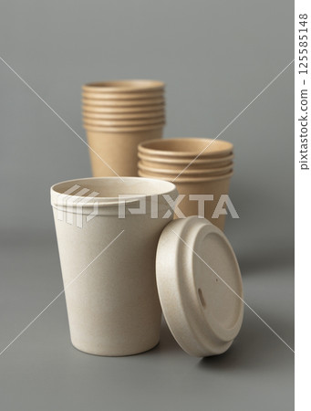 New beige kraft paper cups and reusable bamboo coffee cup with a lid on a gray closeup, mockup New beige kraft paper cups and reusable bamboo coffee cup with a lid on a gray closeup, mockup 125585148
