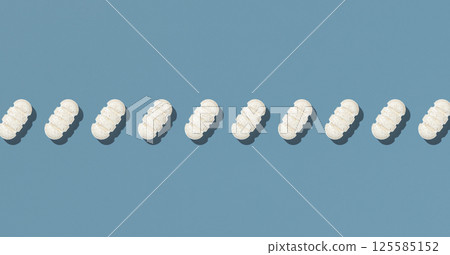 Beige medical pills in a line on blue top view, hard light. pharmaceutical products for healthcare Beige medical pills in a line on blue top view, hard light. pharmaceutical products for healthcare 125585152