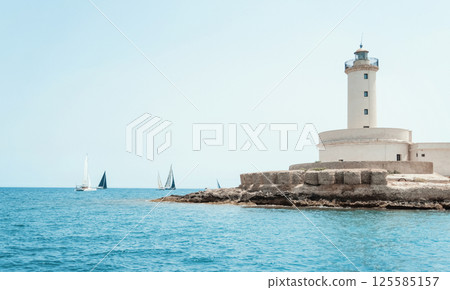 Seascape with sailboats and Brindisi lighthouse island under blue cloudless sky Seascape with sailboats and Brindisi lighthouse island under blue cloudless sky 125585157