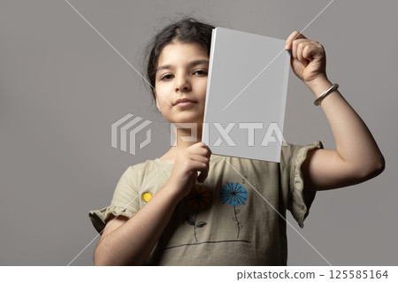 Little girl holding a novel book inside hands with blank cover mock-up series  125585164