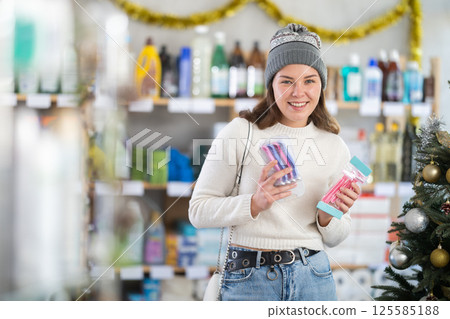 Young woman choosing razor in retail store with New Year decoration 125585188