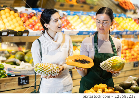 Woman consults a seller about choosing a papaya 125585232