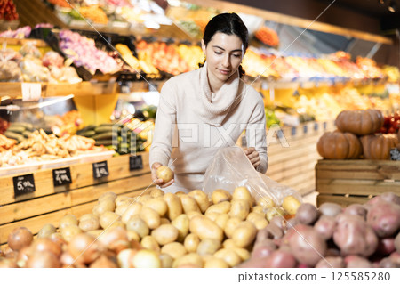 Young woman choosing potatoes in vegetable shop Young woman choosing potatoes in vegetable shop 125585280