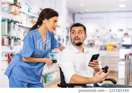 Female pharmacist advising disabled man in drugstore Female pharmacist advising disabled man in drugstore 125585340