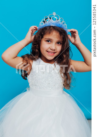 Curly Little Girl in White Princess Dress on Blue Background Curly Little Girl in White Princess Dress on Blue Background 125585341