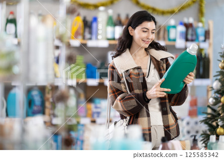 Young woman choosing detergent in New Year's supermarket 125585342