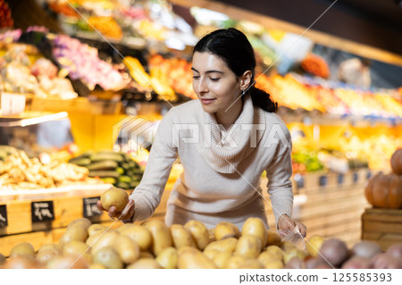 Woman choosing potatoes in a vegetable shop Woman choosing potatoes in a vegetable shop 125585393