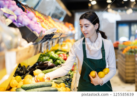 Woman staff with lemon in hands in greengrocery 125585639
