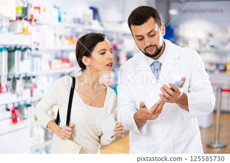 Female buyer consults the pharmacist which lotion or ointment to buy at pharmacy Female buyer consults the pharmacist which lotion or ointment to buy at pharmacy 125585730