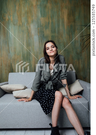 Beautiful fashionable woman sitting on gray office sofa Beautiful fashionable woman sitting on gray office sofa 125585749