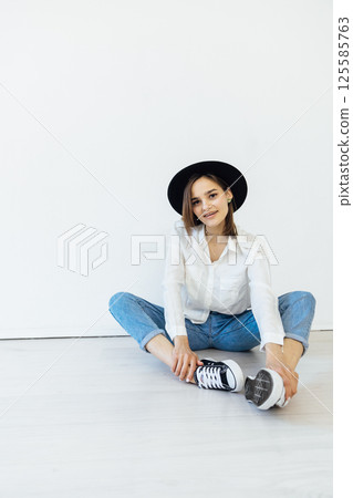 woman in black hat sitting on floor in white room 125585763