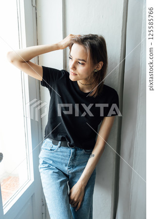 brunette woman posing in photo studio and smiling while sitting on chair 125585766