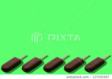 Pattern of ice cream in chocolate glaze. Fashionable ice cream in chocolate glaze pattern on a bright green background. 125585887