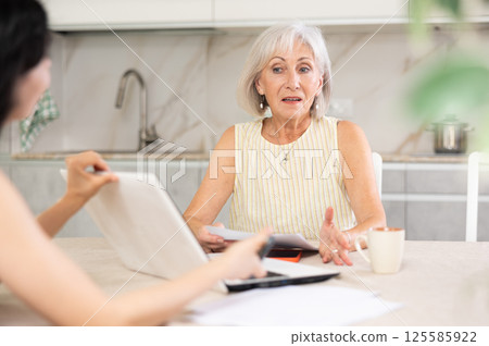 Mature woman meeting financial advisor for investment at home Mature woman meeting financial advisor for investment at home 125585922