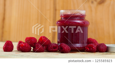 Image of tasty raspberry jam in jar and fresh berries on wooden surface Image of tasty raspberry jam in jar and fresh berries on wooden surface 125585923