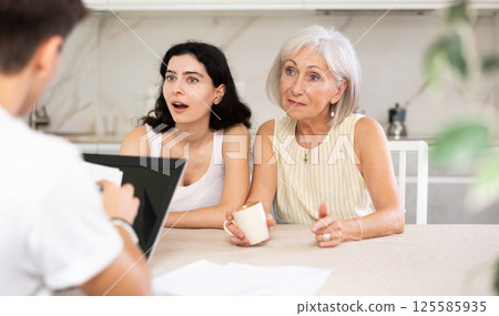 Male realtor is discussing the terms of real estate sale with an elderly woman and her adult daughter 125585935