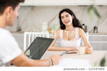 Young woman discussing deal with salesman in kitchen Young woman discussing deal with salesman in kitchen 125585969