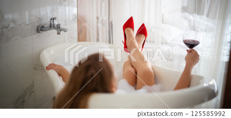 Beautiful woman legs in red high heel shoes with red wine. 125585992
