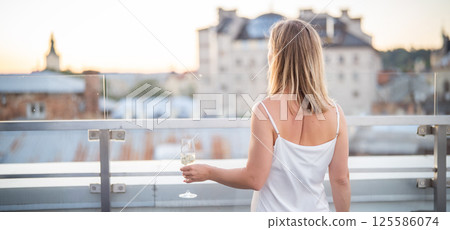 Beautiful woman with a glass of red wine on the terrace 125586074