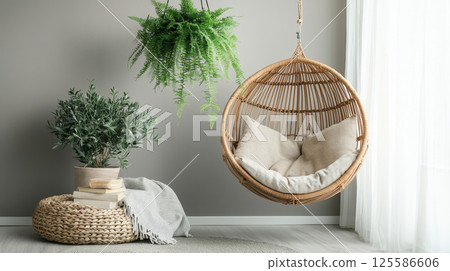 Cozy eco-friendly reading nook with hanging rattan chair and greenery. concept of sustainable home decor, relaxing indoor space, serene ambiance, natural lifestyle 125586606