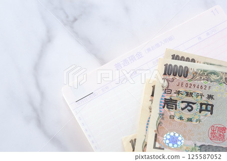 An open bank passbook and a 10,000 yen note on a table An open bank passbook and a 10,000 yen note on a table 125587052