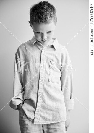 Portrait of young sad boy keeping hand in pocket. Upset kid in casual clothes posing on white background. Black and white image. 125588510