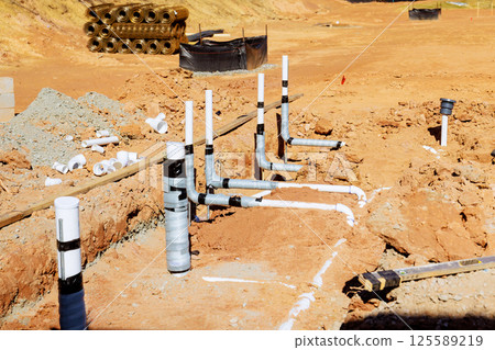 Workers are laying down wastewater plumbing pipes, ensuring proper installation for residential building Workers are laying down wastewater plumbing pipes, ensuring proper installation for residential building 125589219
