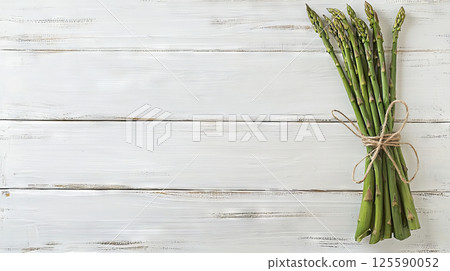 Bundle of Fresh Green Asparagus Tied with Twine on Rustic Wooden Background. Concept of Healthy Cooking, Fresh Produce, Spring Vegetables, Farm-to-Table, Copy space 125590052