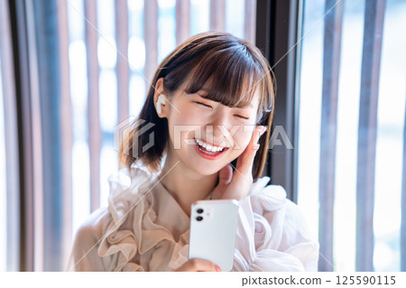 A young woman listening to music on a smartphone A young woman listening to music on a smartphone 125590115