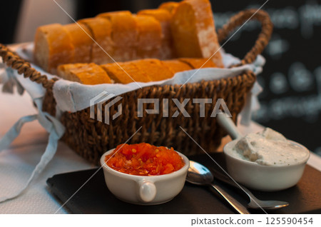 Rustic bread basket with freshly sliced baguette served with tomato and cream dips 125590454