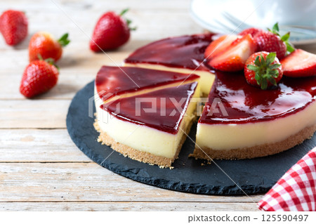 Slice of cheesecake with strawberries on wooden table Slice of cheesecake with strawberries on wooden table 125590497