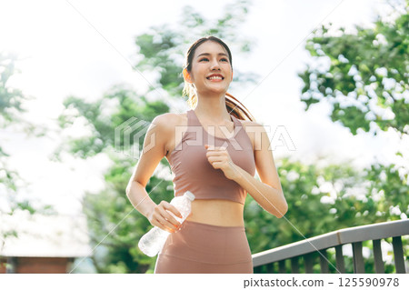 Southeast asian woman smiling running jogging at outdoors park in the morning 125590978