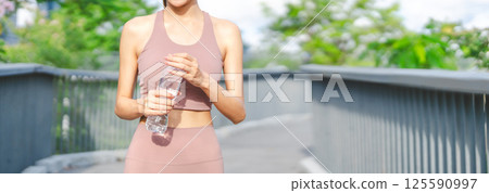 Asian woman rest form running cardio workout cooling down drinking mineral water pet bottle 125590997