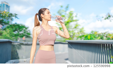 Asian woman rest form running cardio workout cooling down drinking mineral water pet bottle 125590998