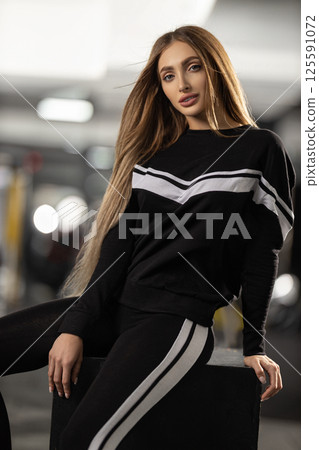 fitness model showcases trendy athletic outfit while posing confidently in contemporary gym setting. atmosphere is energetic and focused on wellness practices. fitness model showcases trendy athletic outfit while posing confidently in contemporary gym setting. atmosphere is energetic and focused on wellness practices. 125591072