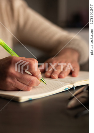 Close up image of human holding pen and writing something on blank white page in notebook. 125591847