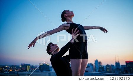 A duo of dancers a man and a woman performing a pas de deux on a rooftop at twilight A duo of dancers a man and a woman performing a pas de deux on a rooftop at twilight 125592170