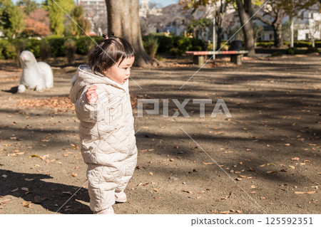 [一歲小孩站在公園裡，在落葉中玩耍] 125592351