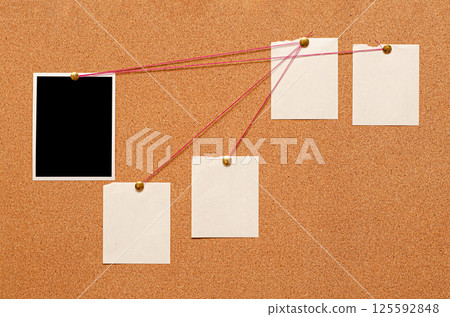 Blank paper notes and an empty photo are pinned to a cork board. The concept of detective investigation. 125592848