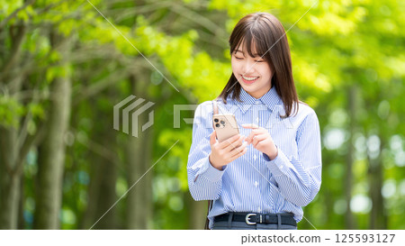Smiling woman/businesswoman using smartphone on promenade Smiling woman/businesswoman using smartphone on promenade 125593127