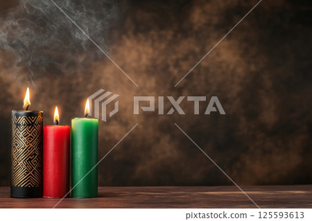Warmly lit Kinara with red, green, and black candles adorned with African patterns against a dark background 125593613